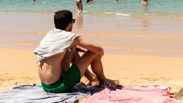 Young male sunbathing and enjoying the view in the picturesque beach