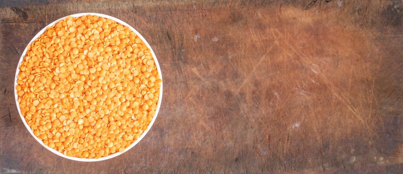 Bowl of uncooked dhal on wooden board