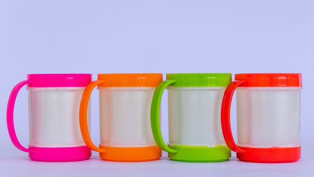 Four colorful plastic coffee mugs lined on a white background