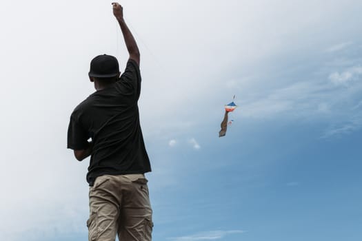 Photograph of a young boy flying a kite on a river bank