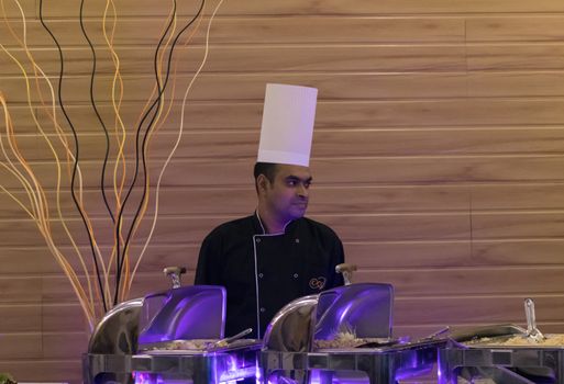 Hikkaduwa, Southern Province / Sri Lanka - 7 23 2020: Chef at the buffet tables with a white chef hat and looking side.