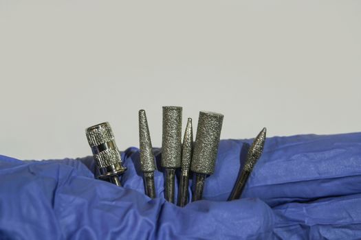 Set of milling cuttersi a manicurist hand. Manicure tool. Used manicurist professional tools in a hand on a white background.
