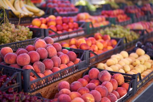 Fruit bazaar peaches nectarine grapes apricots ripe juicy lie plastic box showcase. Seasonal fruits supermarket display