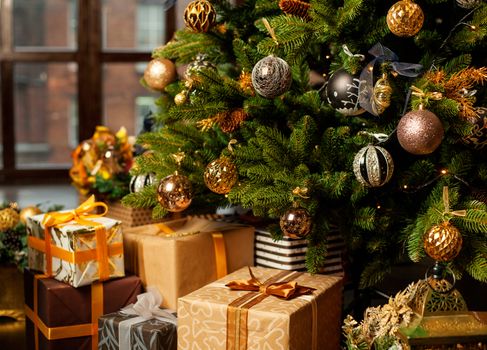 Christmas tree decorated with gold balls. Under the Christmas tree a large number of Christmas gifts. Christmas holiday concept.