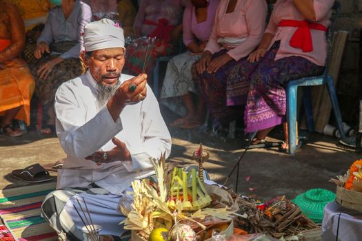 Front view to hindu priest during ceremony. Pedanda sits in front of the sacrifices and performs wedding ceremonies.