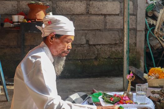 Close up of a Balinese pedanda during prayer. side view of a hindu priest performing a ceremony. A hindu priest performing offerings in a temple in Pemuteran in Bali, Indonesia.