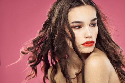 Attractive woman fashionable hairstyle bared shoulders and red lips pink background. High quality photo