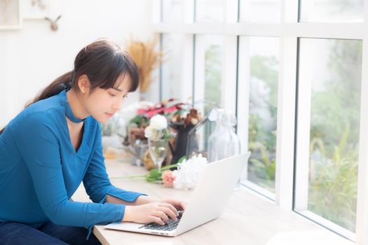 Beautiful portrait asia young woman working online on laptop sitting at cafe shop, professional female freelance using notebook computer, business and communication concept.