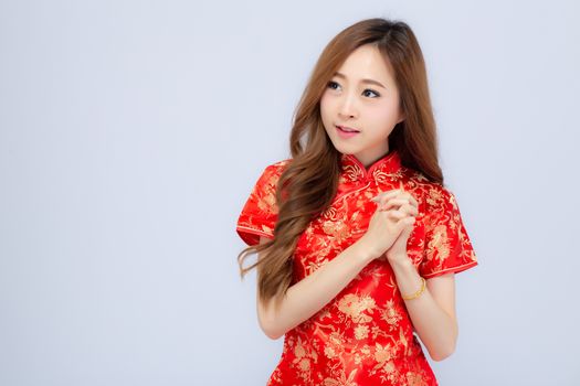 Beautiful portrait happy Chinese New Year young asian woman wear cheongsam smile with gesture congratulation and greeting isolated on white background, festival and celebrate concept.