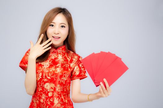 Beautiful portrait young asian woman cheongsam dress smiling holding red envelope on white background, girl celebrate with exciting, happy Chinese New Year, holiday concept.