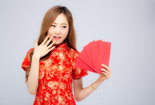 Beautiful portrait young asian woman cheongsam dress smiling holding red envelope on white background, girl celebrate with exciting, happy Chinese New Year, holiday concept.