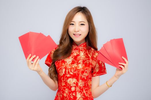 Beautiful portrait young asian woman cheongsam dress smiling holding red envelope on white background, girl celebrate with exciting, happy Chinese New Year, holiday concept.