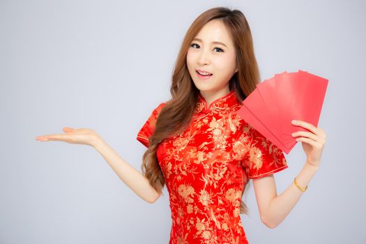 Beautiful portrait asian woman cheongsam dress holding red envelope and presenting something copy space on white background, happy Chinese New Year, holiday concept.