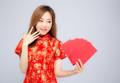 Beautiful portrait young asian woman cheongsam dress smiling holding red envelope on white background, girl celebrate with exciting, happy Chinese New Year, holiday concept.