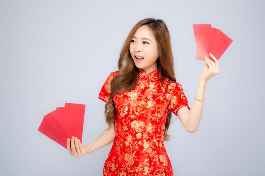 Beautiful portrait young asian woman cheongsam dress smiling holding red envelope on white background, girl celebrate with exciting, happy Chinese New Year, holiday concept.