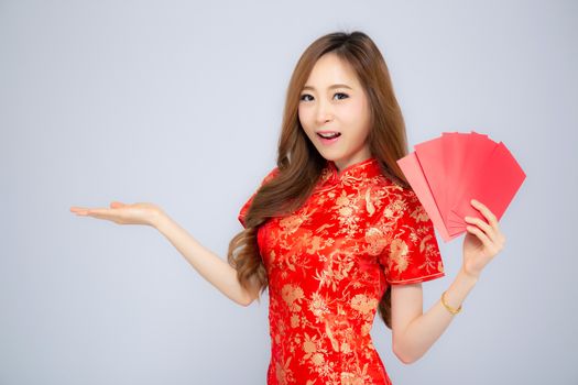 Beautiful portrait asian woman cheongsam dress holding red envelope and presenting something copy space on white background, happy Chinese New Year, holiday concept.