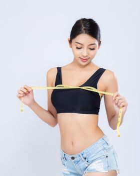 Beautiful portrait asian woman diet and slim with measuring breast and augmentation isolated on white background, girl have cellulite loss with tape measure, health and wellness concept.