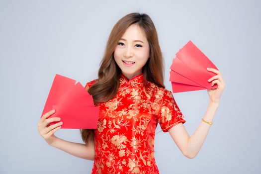 Beautiful portrait young asian woman cheongsam dress smiling holding red envelope on white background, girl celebrate with exciting, happy Chinese New Year, holiday concept.