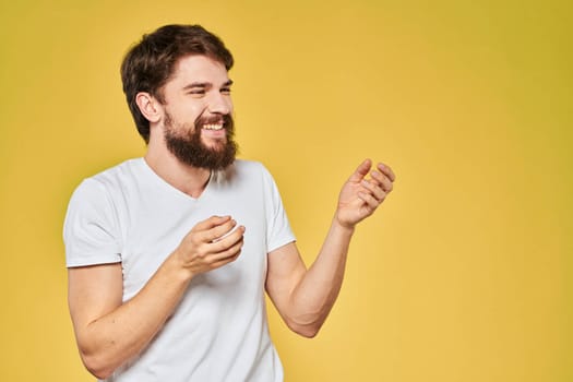 Man gesturing with hands emotions lifestyle white t-shirt yellow isolated background. High quality photo