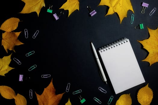 .Autumn fallen foliage and notebook on black background