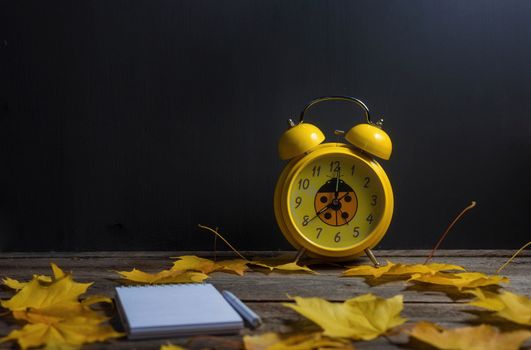 .Still life of autumn fallen leaves and office supplies on a wooden background.