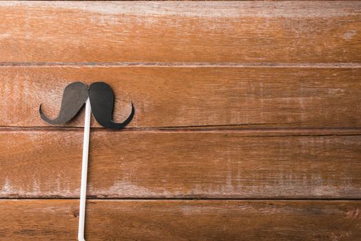 Black mustache paper on wooden background, Prostate cancer awareness month, Fathers day, minimal November moustache concept