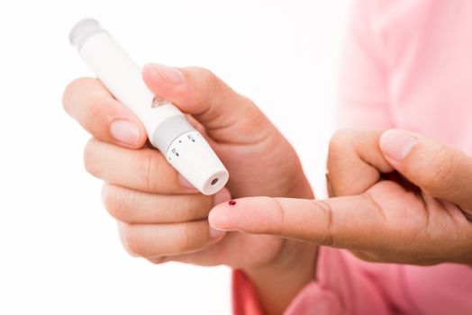 Closeup woman measuring glucose level using a hand test lancelet on the finger she monitors high blood sugar diabetes and glycemic health care concept