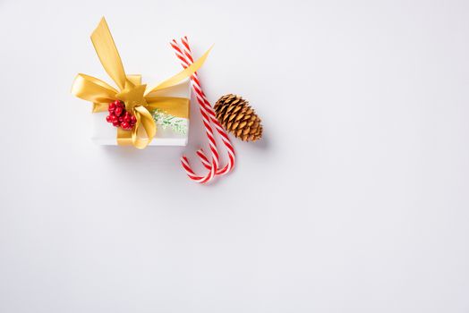 Christmas holiday composition top view flat lay of with a gift box and gold ribbon, fir branches, pine cones, and candy with copy space isolated on white background, New year day concept