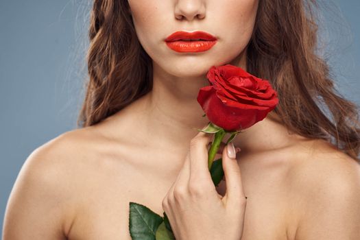 woman with a rose in her hands naked shoulders evening makeup red lips. High quality photo