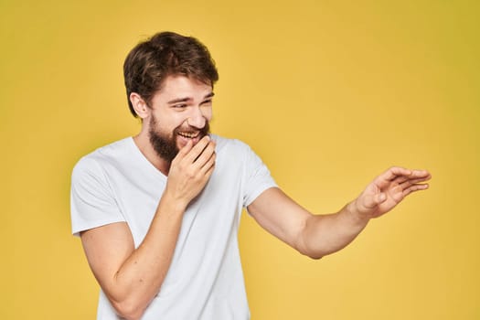 Bearded man white t-shirt emotions gestures with hands fun yellow background. High quality photo