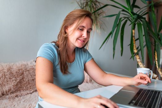 Middle age woman sitting at the table at home working using computer laptop. Work from home and stay at home during coronovirus pandemic concept