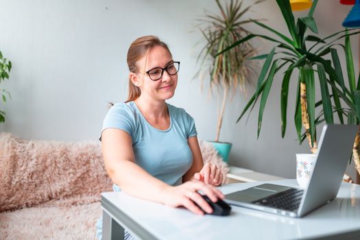 Middle age woman sitting at the table at home working using computer laptop. Work from home and stay at home during coronovirus pandemic concept