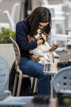 terni,italy september 02 2020:girl holding a little dog sitting at the bar