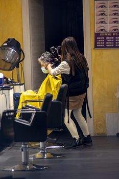 terni,italy september 02 2020:hairdresser who gives hair to a client with medical masks