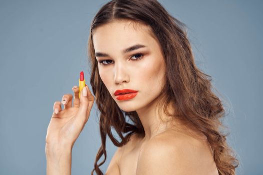 Woman with lipstick on a gray background brunette makeup with eye shadow on the eyelids. High quality photo