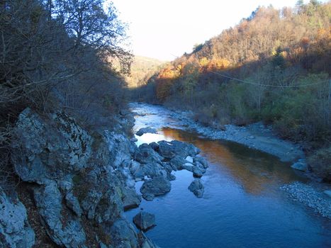 Liguria, Italy -  11/02/2020: Colorful autumn landscape around the village of Tiglieto near the city of Genova. Beautiful sunset reflection in the river and clear blue sky.