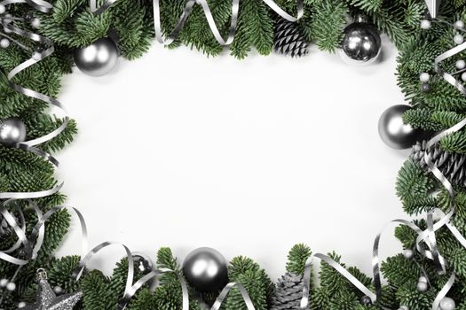Christmas border frame design copmosition of noble fir tree branch and silver decorations balls baubles pine cones isolated on white background