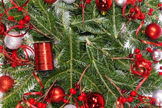 Christmas copmosition of fir tree branch and red decorations balls baubles pine ribbons background