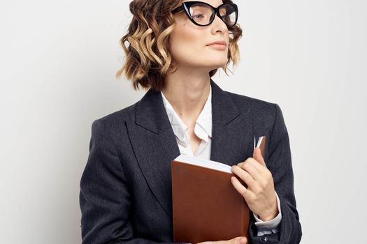 Business woman in a classic suit with a notebook in her hand and glasses on her face Copy Space. High quality photo