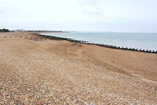 Deserted shingle beach in Eastbourne on the south coast of England. Shingle and sand leads down to the sea on a cloudy day.