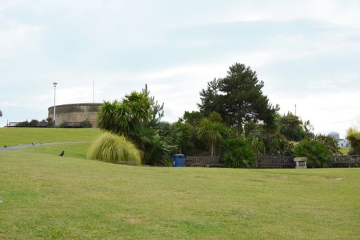 Grass slope with seating, shrubbery and trees in front of the historic Redoubt fortress on Royal Parade in Eastbourne
