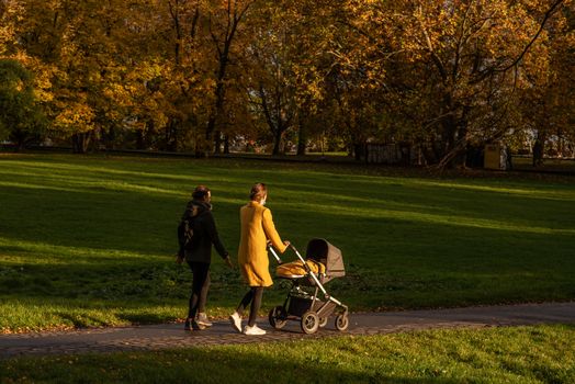 Two woman (one carrying a baby stroll) are enjoying a walk Autumn 2020 on Prague 6, during quarantine period due to outbreak of COVID-19 as winter is starting, Czech Republic