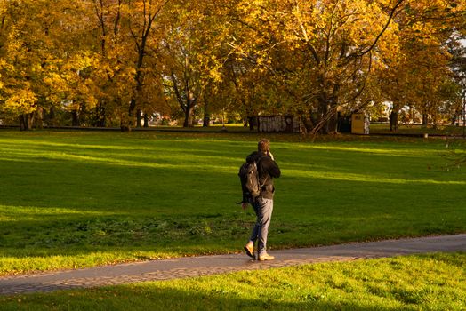 A man is speaking on a phone while walking on Park Letna in Autumn 2020 on Prague 6, during quarantine period due to outbreak of COVID-19 as winter is starting, Czech Republic