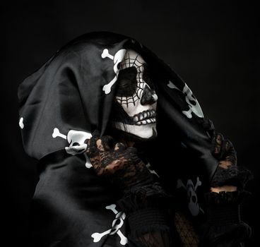 portrait of a woman in a make-up of a skeleton dressed in a black cloak with a cap, festive image for Halloween