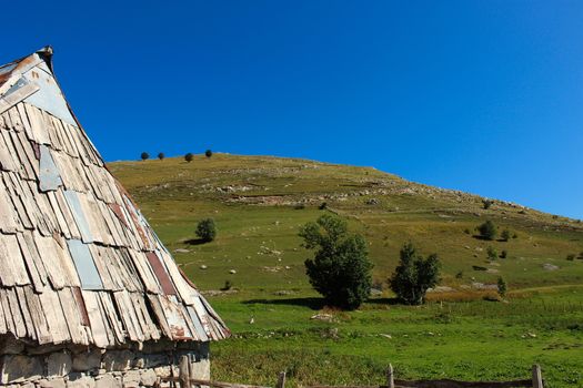 Part of the house and the roof of a Bosnian house with a view of the hill behind, in the old Bosnian village of Lukomir on the Bjelasnica mountain.