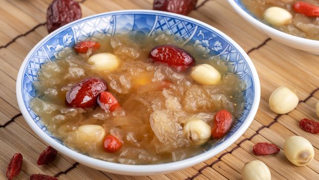 Close up of traditional Chinese sweet snow white fungus soup with lotus seed, red dates (jujube) and wolfberry (goji berry, gojiberry) on white background.