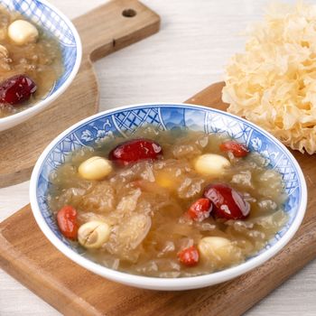 Close up of traditional Chinese sweet snow white fungus soup with lotus seed, red dates (jujube) and wolfberry (goji berry, gojiberry) on white background.