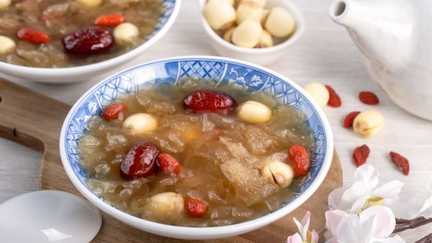 Close up of traditional Chinese sweet snow white fungus soup with lotus seed, red dates (jujube) and wolfberry (goji berry, gojiberry) on white background.