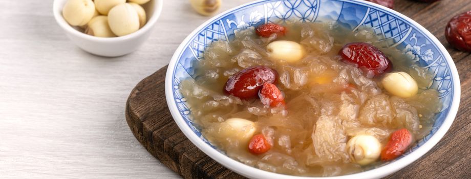 Close up of traditional Chinese sweet snow white fungus soup with lotus seed, red dates (jujube) and wolfberry (goji berry, gojiberry) on white background.