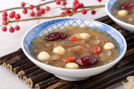 Close up of traditional Chinese sweet snow white fungus soup with lotus seed, red dates (jujube) and wolfberry (goji berry, gojiberry) on white background.